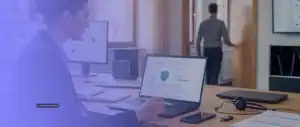 Microsoft Defender for Business: KI-visualisierte Darstellung einer IT-Verantwortlichen, die den Sicherheitsstatus eines Firmen-Notebooks mit weiteren Unternehmensgeräten prüft.